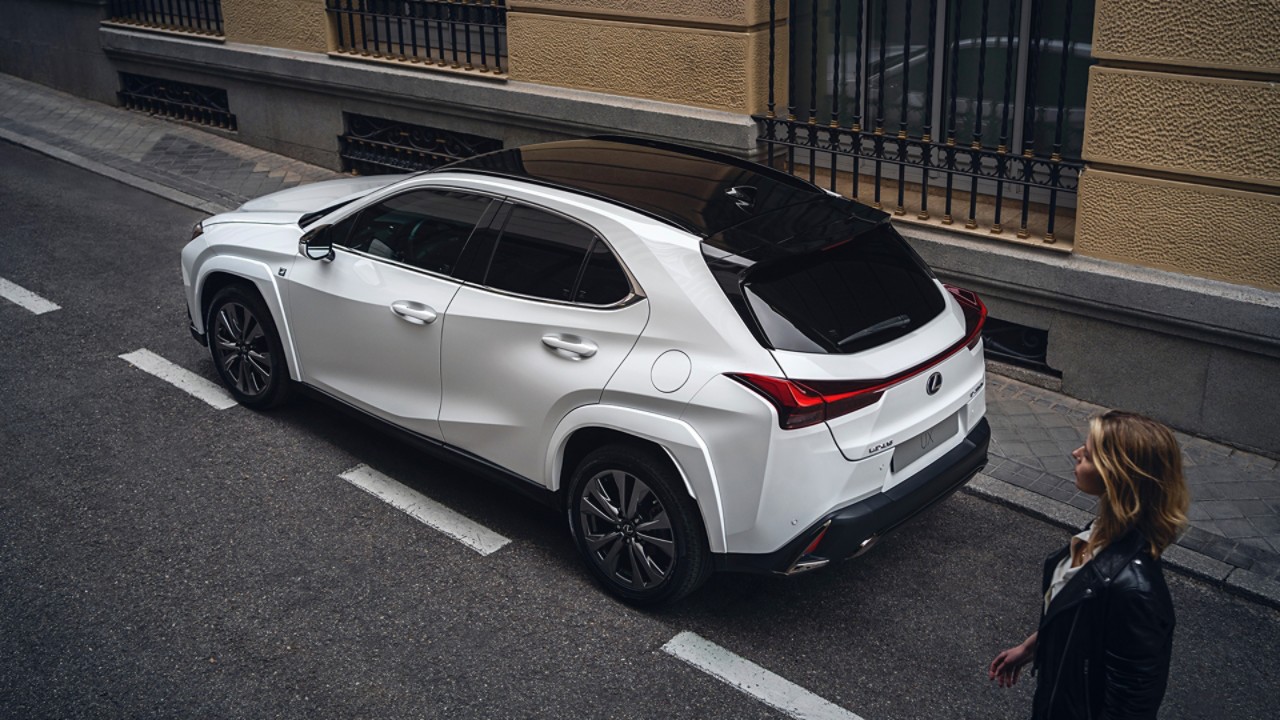 A woman walking towards a Lexus UX