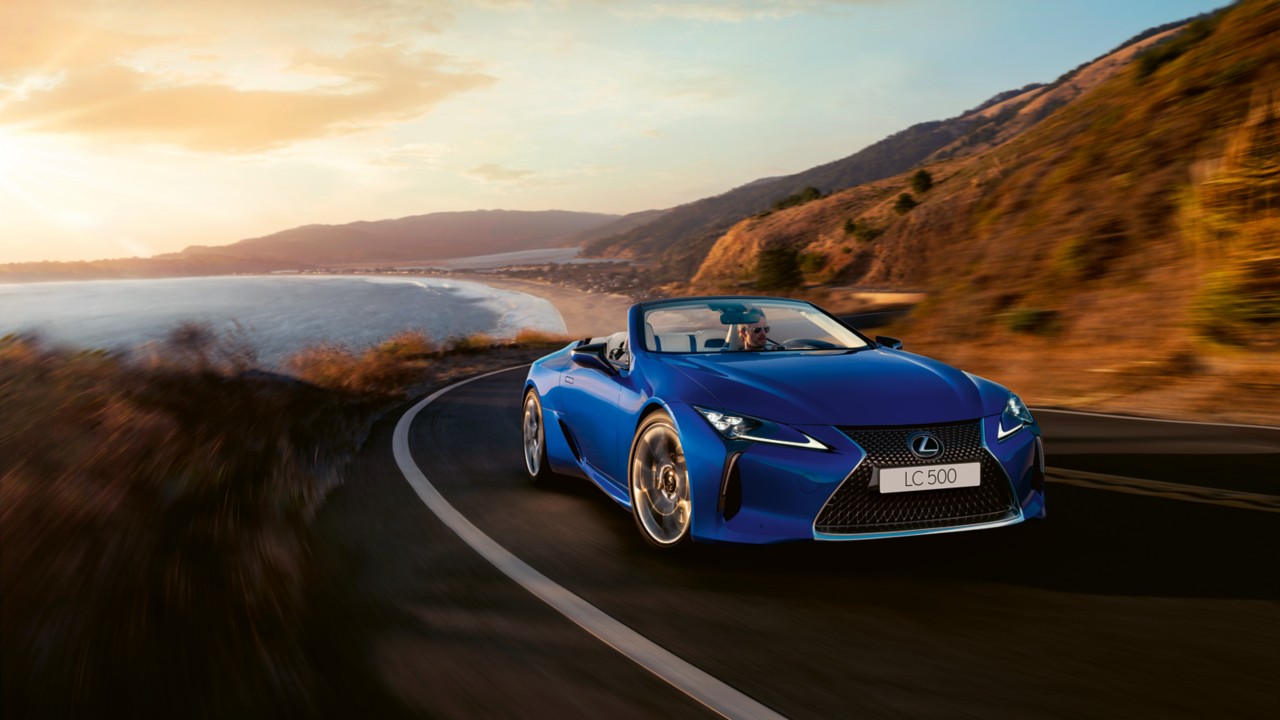 Lexus LC convertible driving around a corner in a mountainous location 