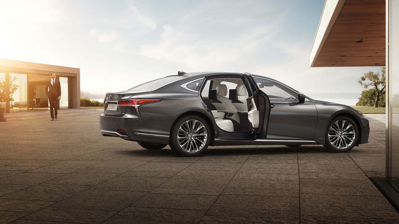 A man approaching a Lexus LS with it's rear passenger door open 