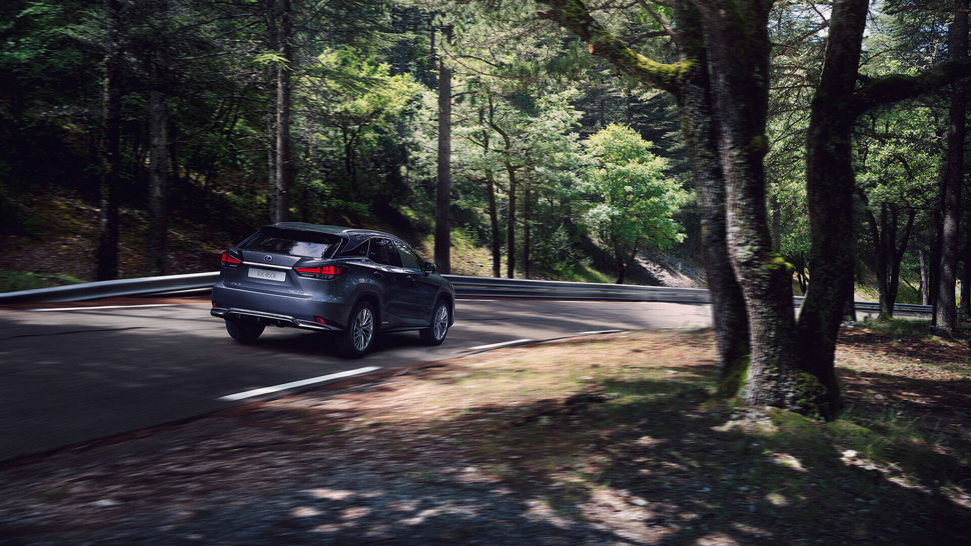 A Lexus RX 450h driving on a woodland road